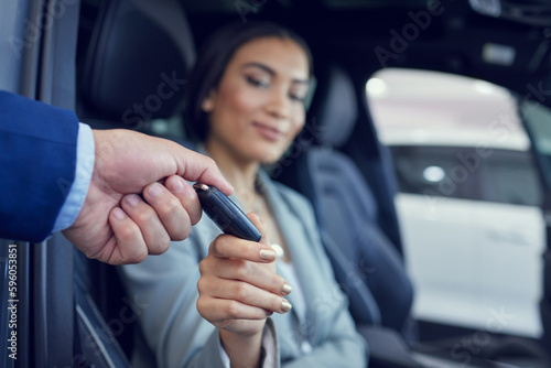 Why dont you fire her up. Closeup shot of an unrecognizable male car salesman handing a key to an attractive female client. © Azeemud-Deen Jacobs/peopleimages.com