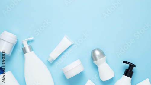 Cosmetic beauty products on blue background. Bottles and tubes with branding mock up. Skin care and beauty concept. Top view, flat lay, copy space