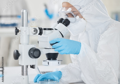 Supporting scientific investigations with detailed analysis. a scientist wearing a radiation suit while using a microscope in a lab.