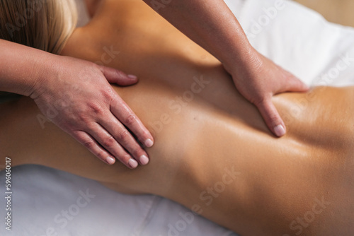 Close up cropped shot of unrecognizable male masseur doing back and shoulder massage to female client with beautiful skin lying in spa salon. Concept of healthy lifestyle and body care.