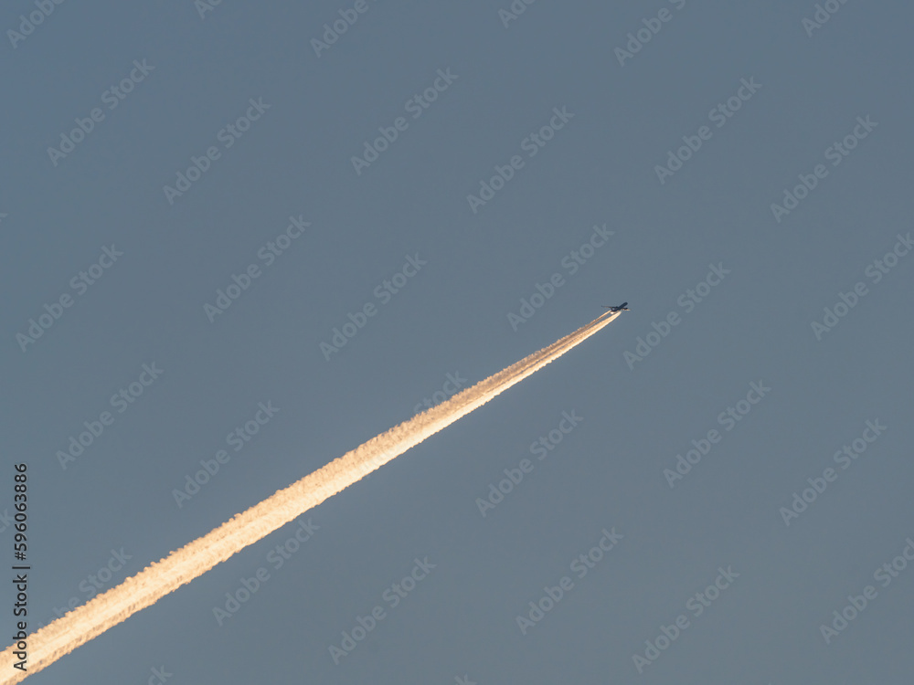 The plane flies in the blue sky and leaves a bright trail The plane flies in the blue sky and leaves a bright trail