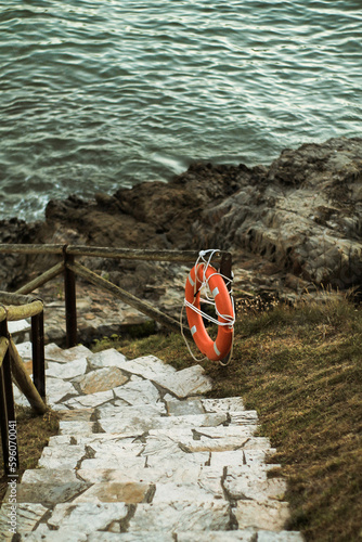 Descending to the Ocean: Stairs Leading to the Waves and Sandy Beach, Lifeguard Station and Red Rescue Buoy on Guard, Serene Blue Sky and Calm Seascape in the Background
