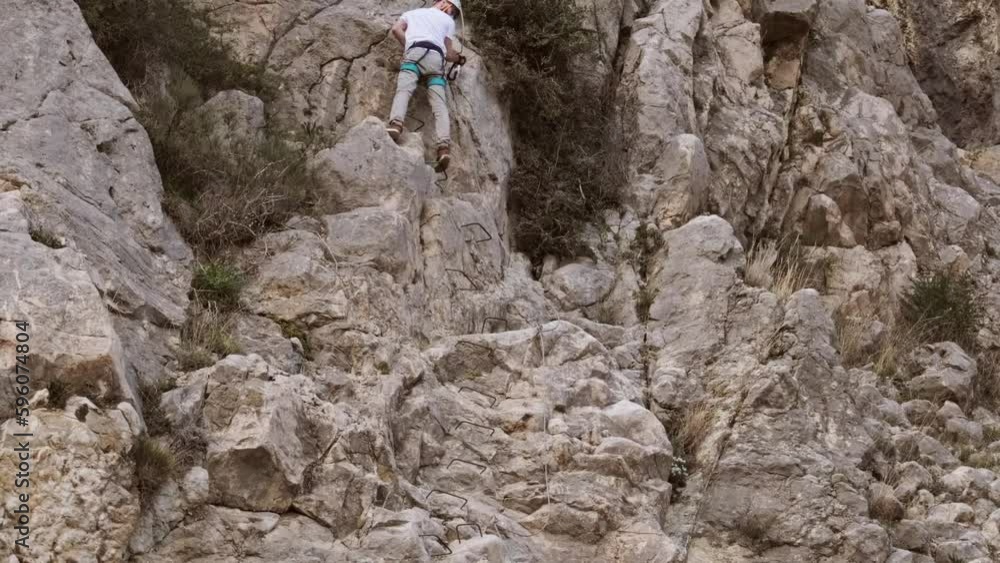 young man in body harnesses feature life-safety, attaches hooks to iron brackets, climbs rock, extreme lifestyle of people, mountaineering, via ferrata in mountains, life insurance in extreme sports young man in body harnesses feature life-safety, attaches hooks to iron brackets, climbs rock, extreme lifestyle of people, mountaineering, via ferrata in mountains, life insurance in extreme sports