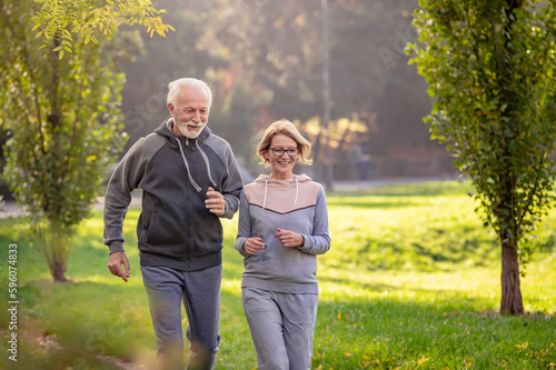 Smiling senior couple jogging in the park. Sports activities for elderly people © lordn