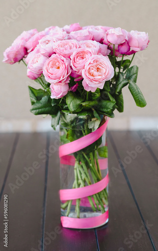 Fototapeta Naklejka Na Ścianę i Meble -  A vase of pink roses with a pink ribbon around it.