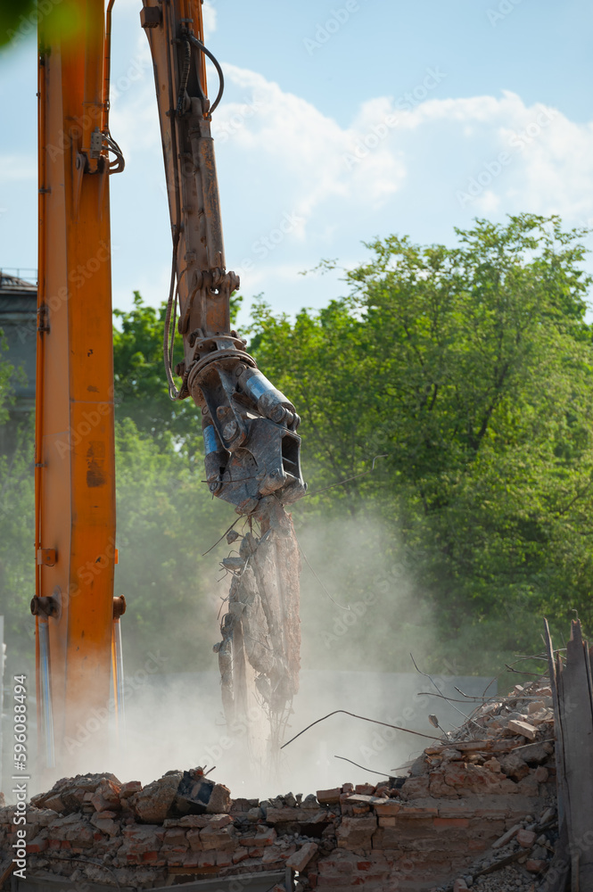 Fototapeta premium Demolition of building. Excavator breaks old house. Freeing up space for construction of new building