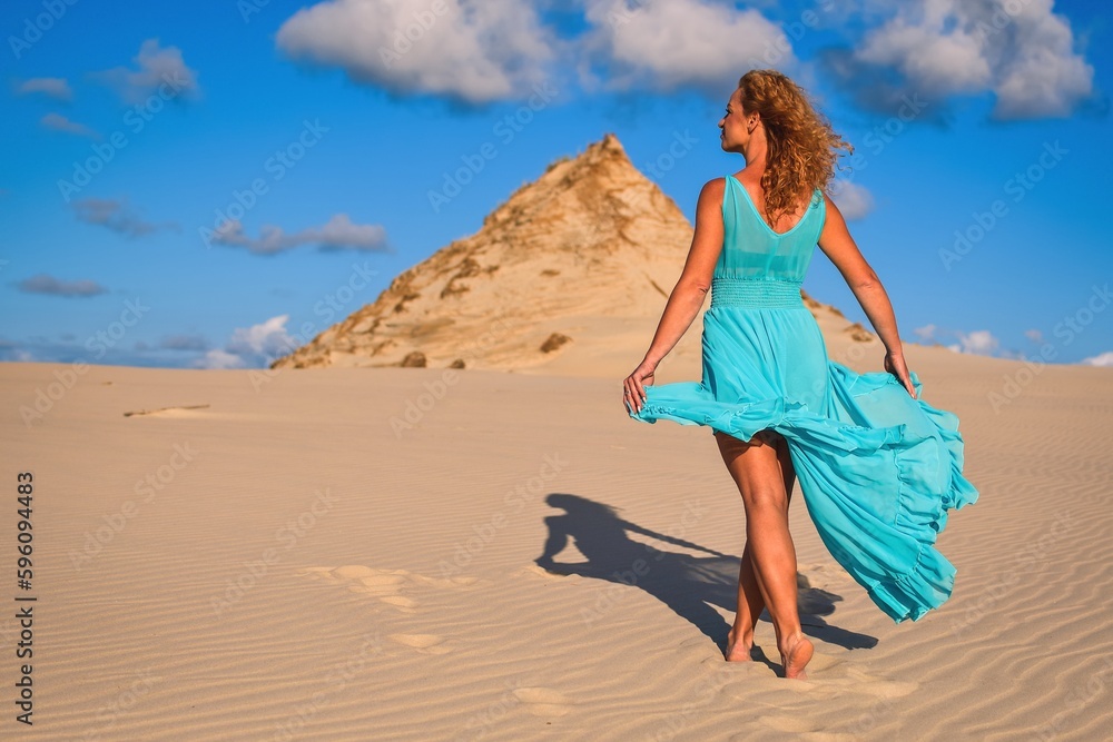Beautiful blonde woman on hot sand with blue sky in the background. Photo taken on the shifting dunes over the Baltic Sea in Leba, Poland. Photo with a shallow depth of field with blurred background. Beautiful blonde woman on hot sand with blue sky in the background. Photo taken on the shifting dunes over the Baltic Sea in Leba, Poland. Photo with a shallow depth of field with blurred background.