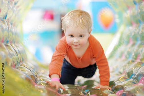 Active toddler boy having fun on inflatable attraction in entertaining center. Funny child is playing on indoor playground. Kids amusement park.