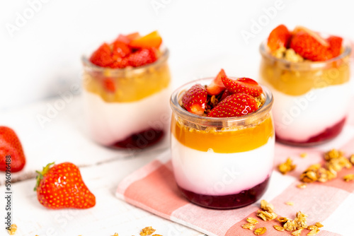 Fruit yogurt berry with muesli and fresh strawberries  on a white wooden background