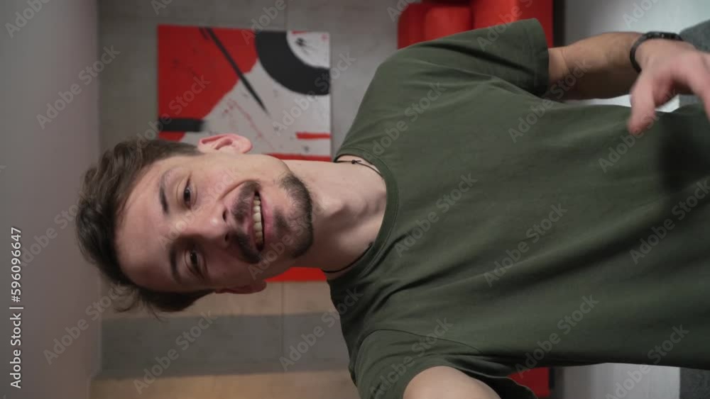 One man young adult caucasian male standing at home with brown hair mustaches and beard looking to the camera happy smile confident talk real people green t shirt UGC selfie user generated content