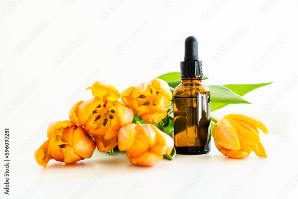 Naklejka premium Amber glass cosmetic dropper bottle and orange tulips isolated on white background, serum bottle mockup