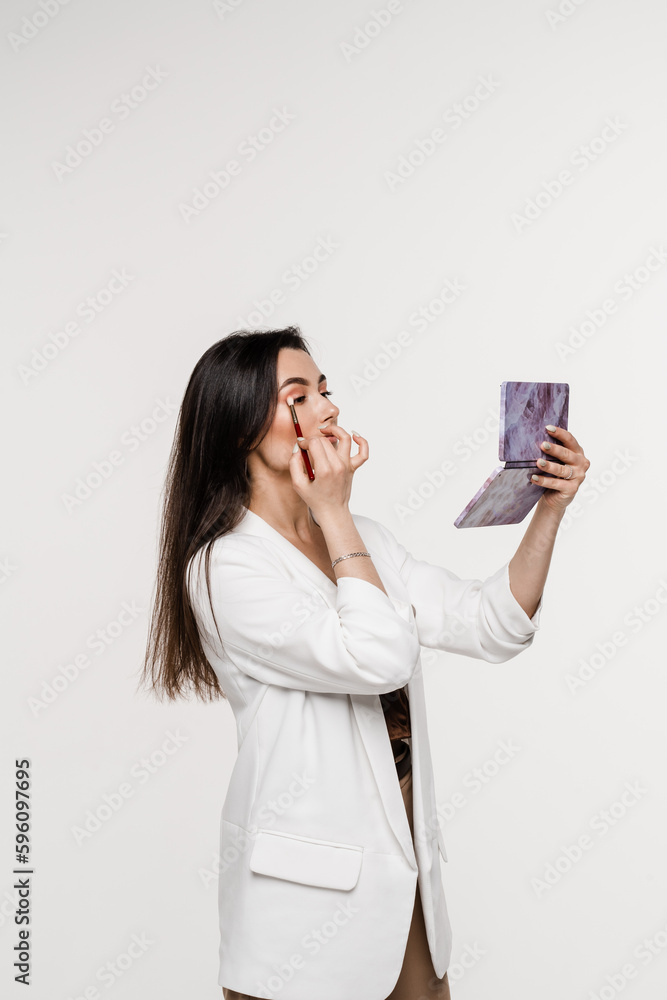Girl does herself makeup with brush using color palette to draw shadows on her eyes. Professional cosmetics for make-up artist for perfect skin. Girl does herself makeup with brush using color palette to draw shadows on her eyes. Professional cosmetics for make-up artist for perfect skin.