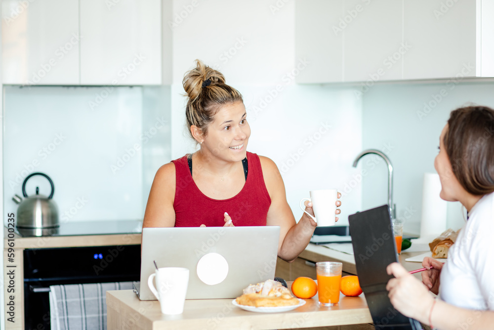 Two young pretty women sitting with laptops facing each other. Businesswoman. Working women. Home office, startup.