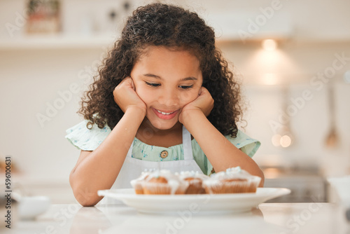 I dont know if I could wait any longer. a little girl patiently waiting to eat the freshly baked cupcakes.