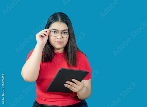 Portrait business girl young woman asian chubby fat cute beautiful pretty one person wearing red shirt in office holding digital tablet and smiling standing with copy space on isolated blue blackgrond photo