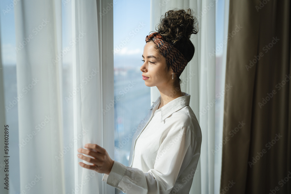One woman beautiful caucasian stand by the window at home or hotel One woman beautiful caucasian stand by the window at home or hotel