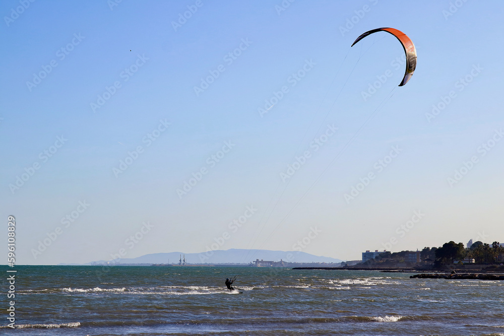 Kitesurfer flying over the waves in Ebro river delta national park, one of the most amazing spots in the Spanish seaside (all brand names and logos removed from the kite and the board).
