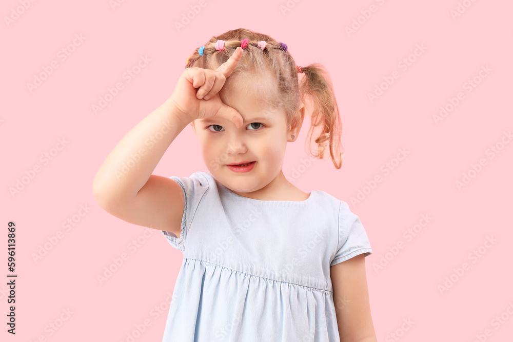 Funny little girl showing loser gesture on pink background Funny little girl showing loser gesture on pink background