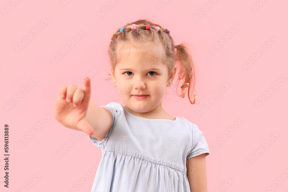 Funny little girl showing loser gesture on pink background Funny little girl showing loser gesture on pink background