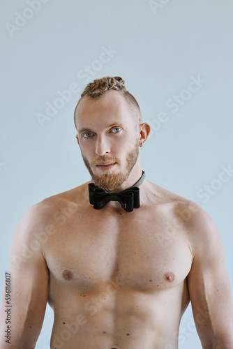 Portrait of handsome caucasian athletic young man topless in leather bow tie. Fitness, bodybilding  photo