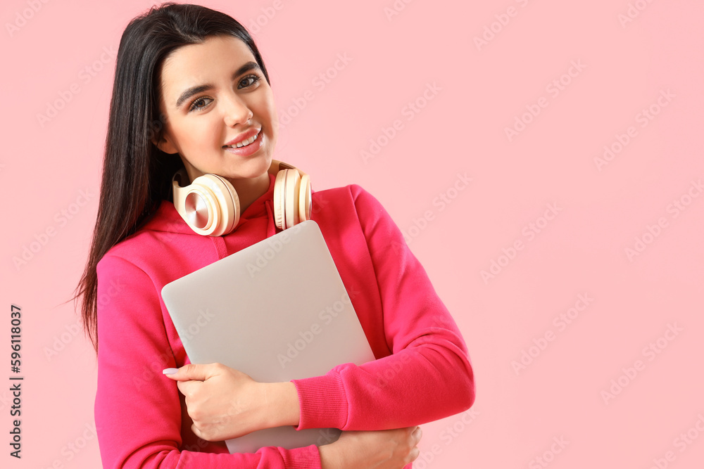 Fototapeta premium Young female programmer with laptop on pink background