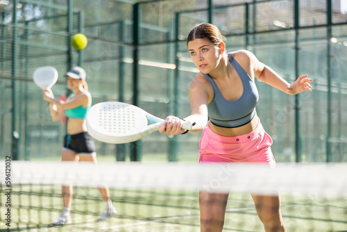 Determined sporty young woman doing her best playing padel in court