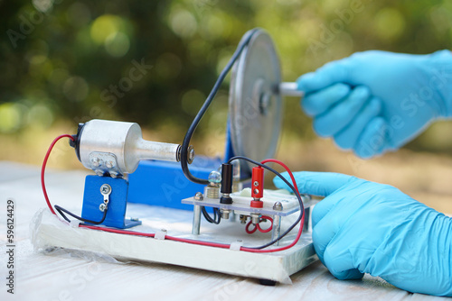 Vászonkép Close up hands wear blue gloves demonstrate science experiment about electricity circuit from dynamo kit for teaching