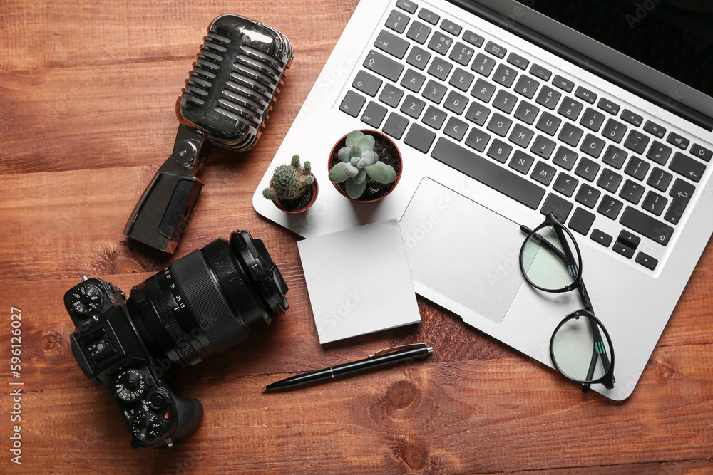 Laptop with eyeglasses, sticky notes, microphone and photo camera on wooden background Laptop with eyeglasses, sticky notes, microphone and photo camera on wooden background