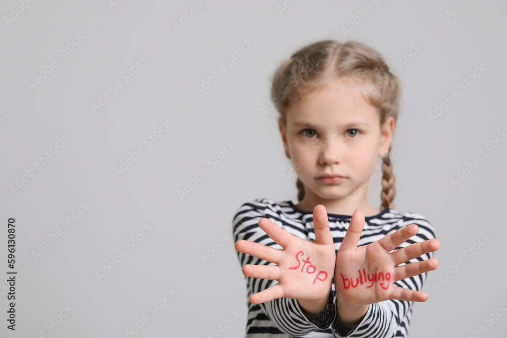 Girl showing hands with phrase Stop Bullying on light grey background, selective focus. Space for text Girl showing hands with phrase Stop Bullying on light grey background, selective focus. Space for text