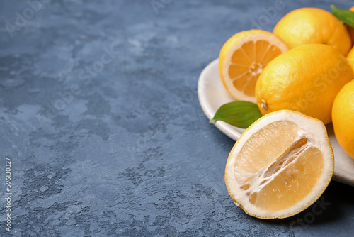 Plate with fresh lemons on blue grunge background