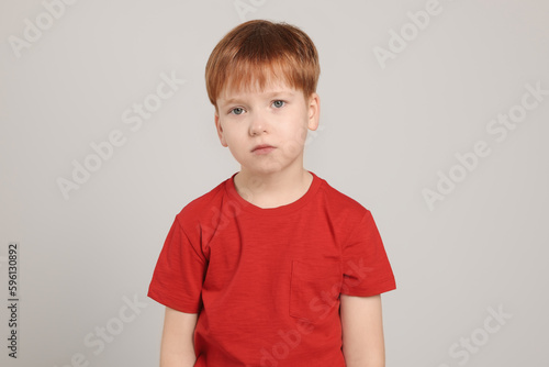 Upset boy on light grey background. Children's bullying