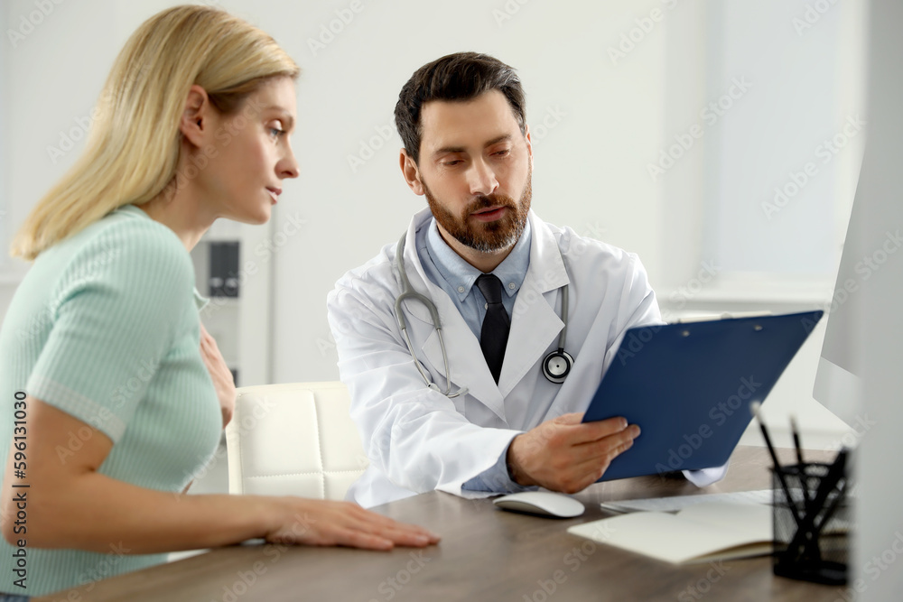 Doctor consulting patient at wooden table in clinic Doctor consulting patient at wooden table in clinic