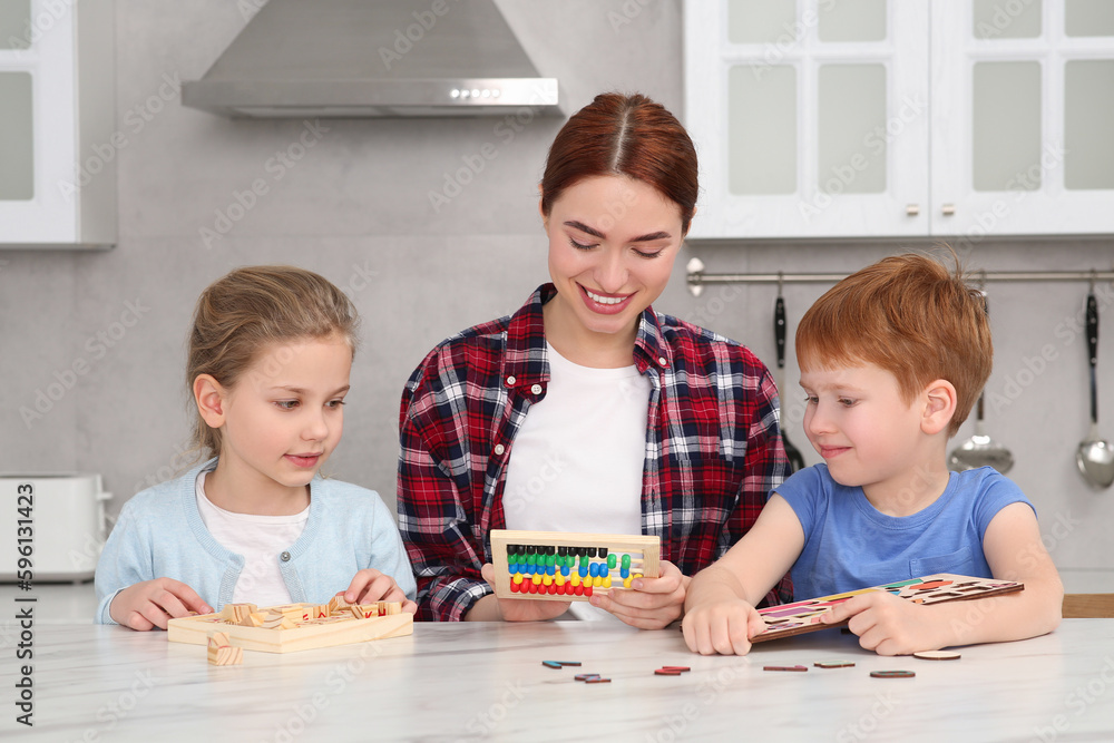 Happy mother and children playing with different math game kits at white marble table in kitchen. Study mathematics with pleasure Happy mother and children playing with different math game kits at white marble table in kitchen. Study mathematics with pleasure