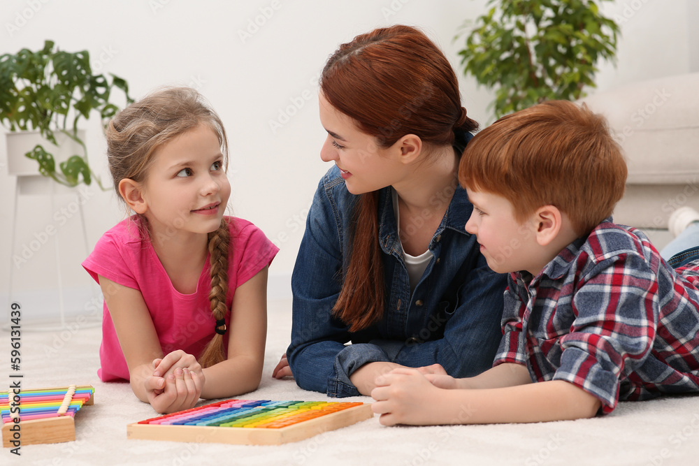 Happy mother and children playing with different math game kits on floor in room. Study mathematics with pleasure Happy mother and children playing with different math game kits on floor in room. Study mathematics with pleasure
