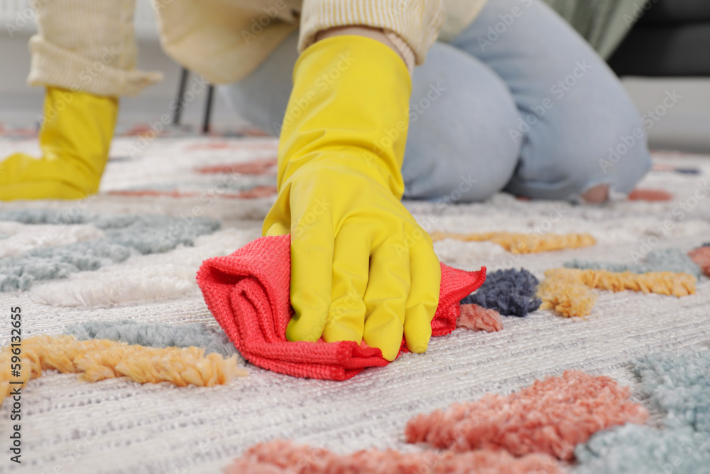 Woman in rubber gloves cleaning carpet with rag indoors, closeup Woman in rubber gloves cleaning carpet with rag indoors, closeup