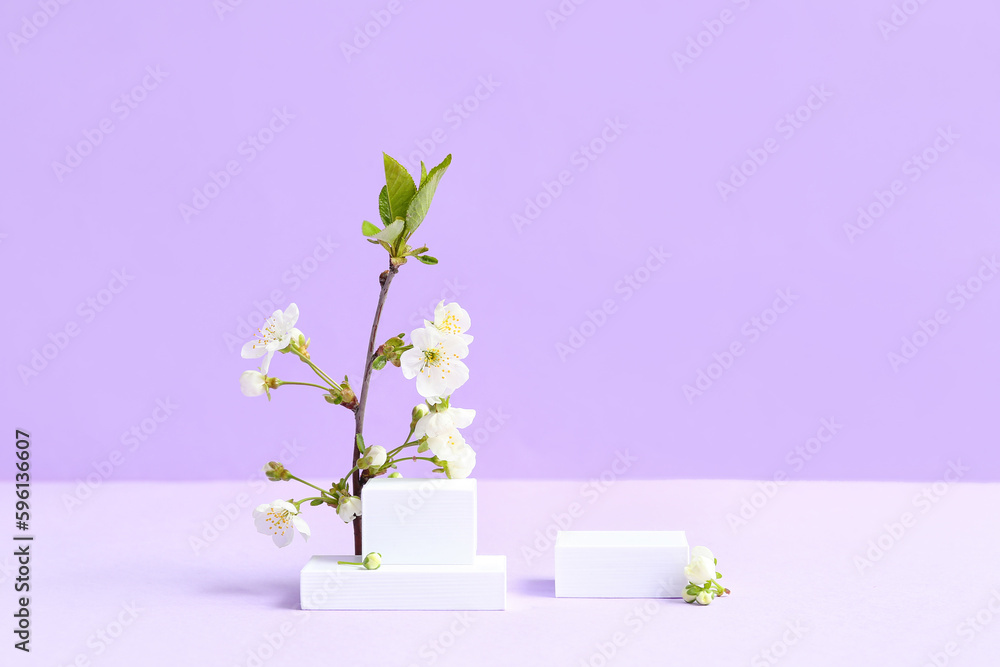 Decorative podiums and blooming branch on lilac background Decorative podiums and blooming branch on lilac background