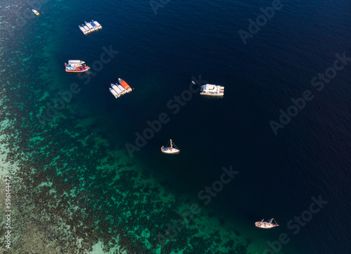 Scenic tropical sea with coral reef and boat sailing in summer