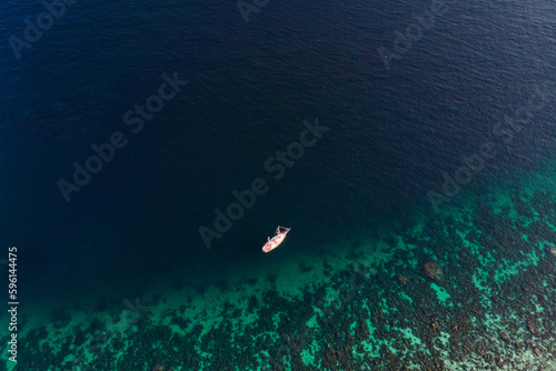 Scenic tropical sea with coral reef and boat sailing in summer