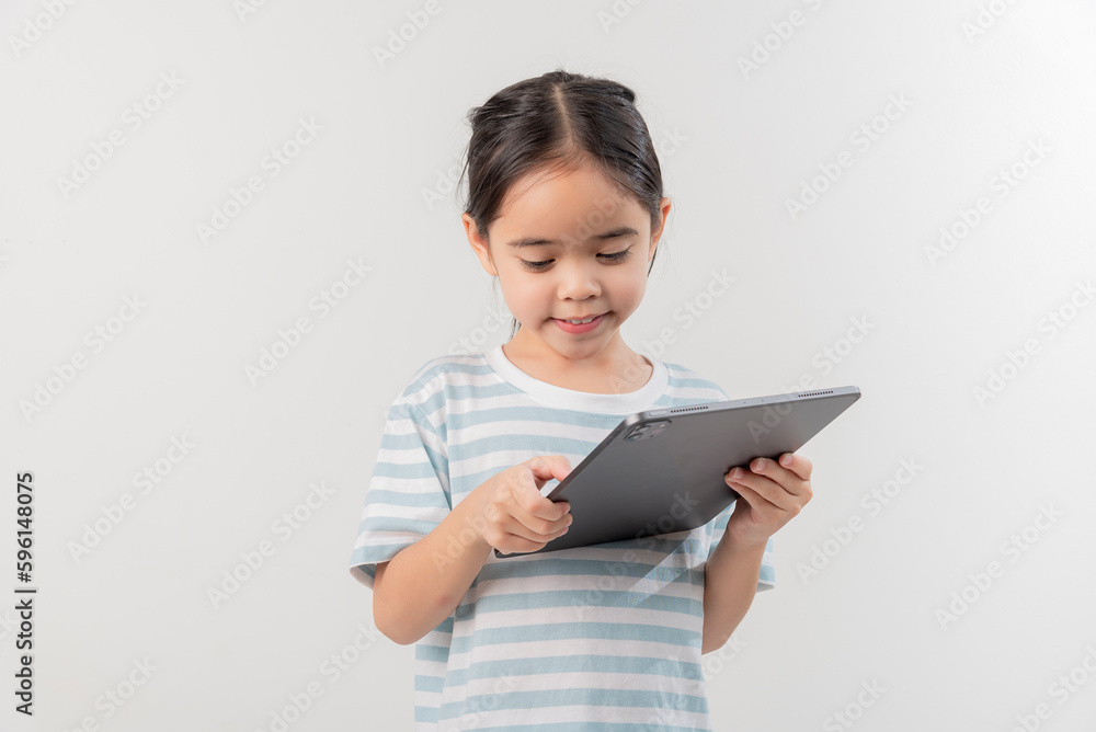 smiling little girl stiiting and holding a tablet smiling little girl stiiting and holding a tablet