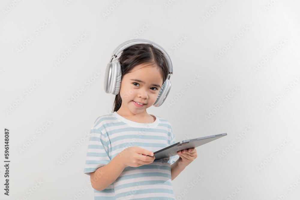 smiling little girl stiiting and holding a tablet with earphone smiling little girl stiiting and holding a tablet with earphone