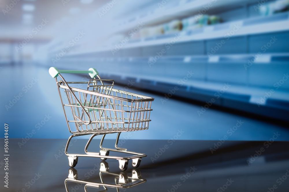 empty shopping cart with aisle with unfocused empty shelves