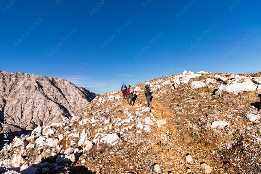 group of hikers walking through volcanic landscape with rocky and arid mountains in Volcan Poas National Park in Alajuela province of Costa Rica