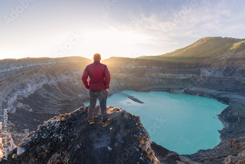 Fotografia Mountaineer man looking at the Poas Volcano Crater Lagoon at sunrise surrounded
