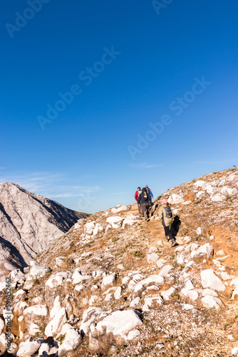 vertical shot of group of hikers walking through volcanic landscape with rocky and arid mountains in Volcan Poas National Park in Alajuela province of Costa Rica