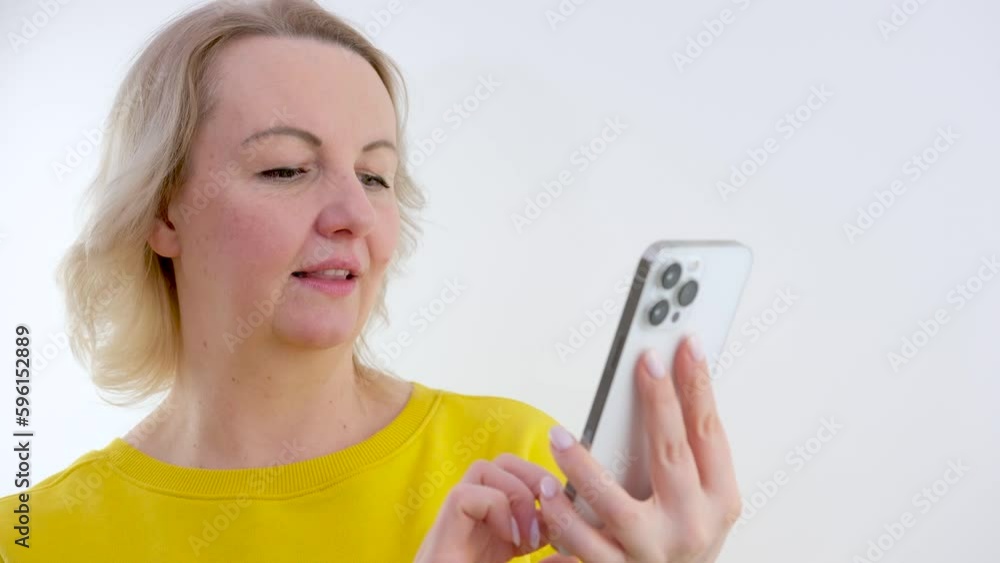 Blonde Ukrainian woman using mobile phone with smile. Young adult blonde female communicating online with modern white smartphone device. Cheerful person texting on messenger app. High quality Blonde Ukrainian woman using mobile phone with smile. Young adult blonde female communicating online with modern white smartphone device. Cheerful person texting on messenger app. High quality