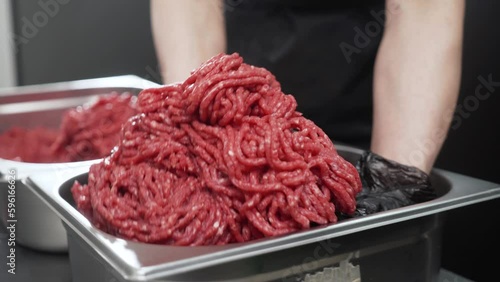 In the hands puts the fresh ground beef into an iron container. minced meat.