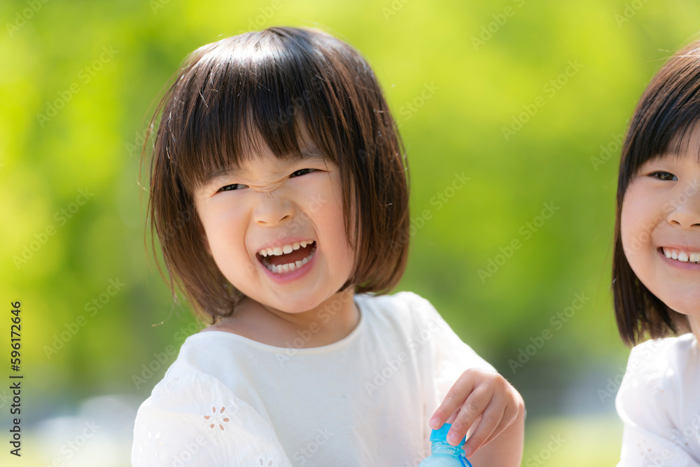 新緑の初夏の公園で遊ぶ小さな姉妹 新緑の初夏の公園で遊ぶ小さな姉妹
