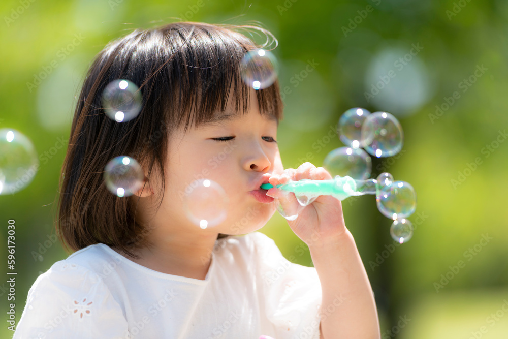 新緑の初夏の公園でシャボン玉をして遊ぶ小さな女の子 新緑の初夏の公園でシャボン玉をして遊ぶ小さな女の子