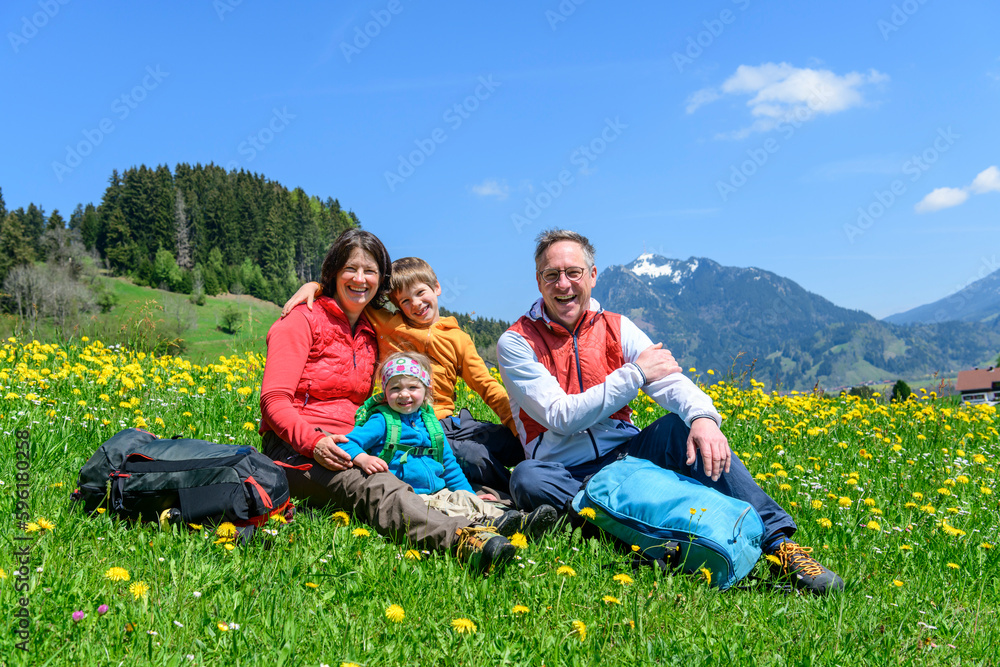 Glückliche Familie sitzt auf einer Wiese im Allgäu Glückliche Familie sitzt auf einer Wiese im Allgäu