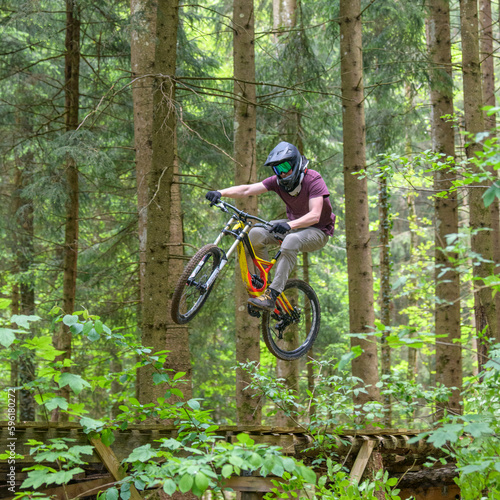 Spektakulärer Flug eines Mountainbikers über eine Rampe im Wald 